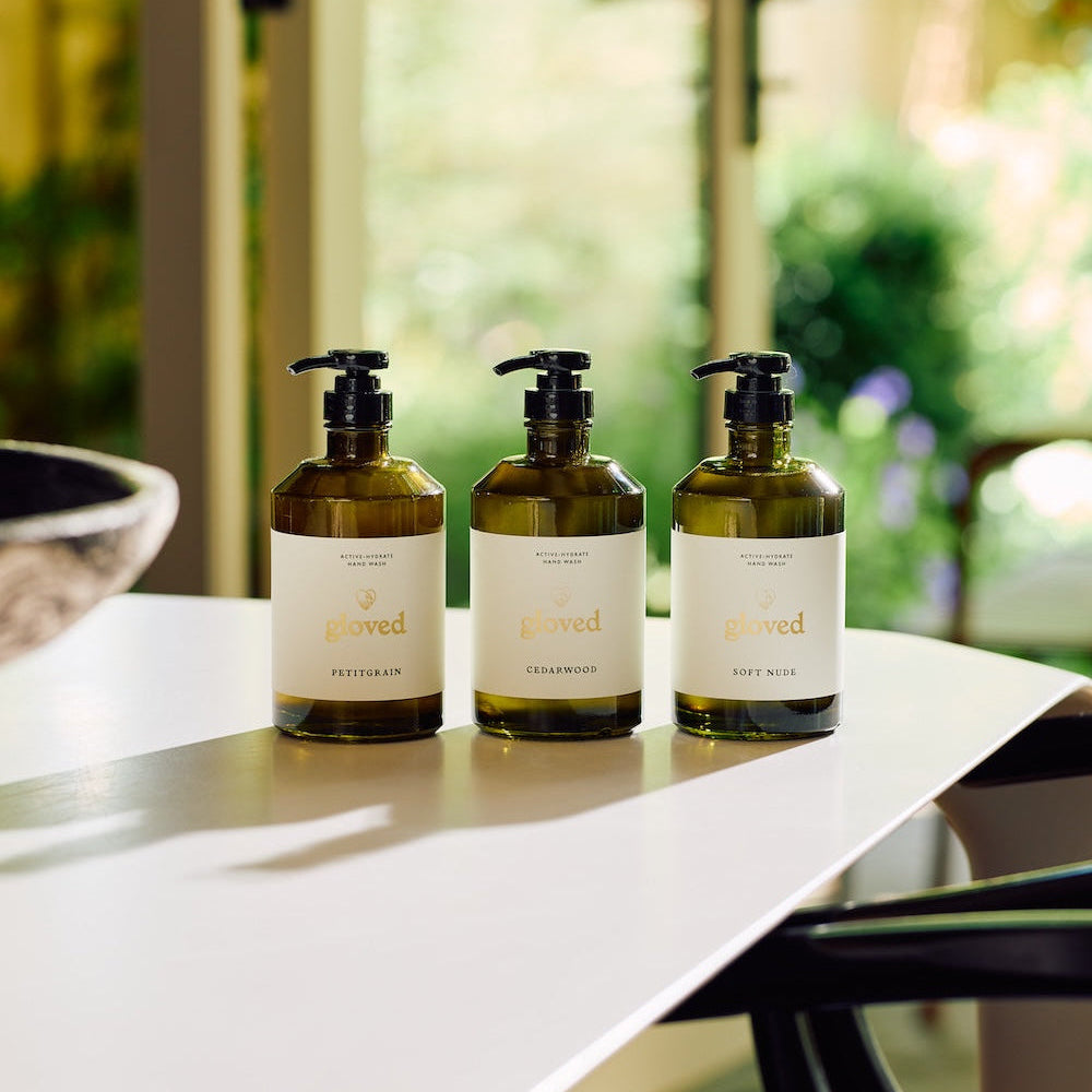 Three gloved hand washes in green glass on a sunlit table