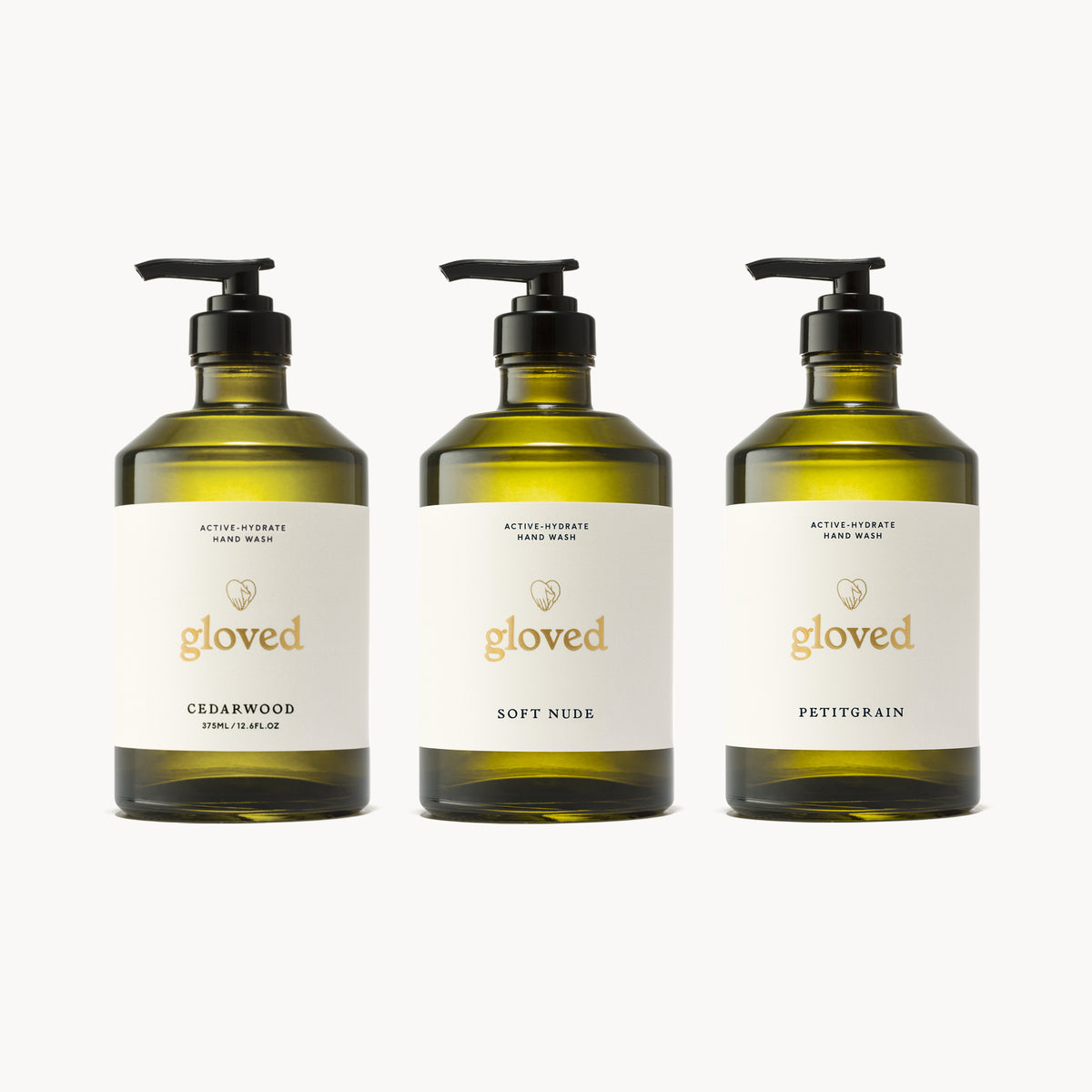Three full-size gloved hand wash bottles in glass: Cedarwood, Soft Nude and Petitgrain